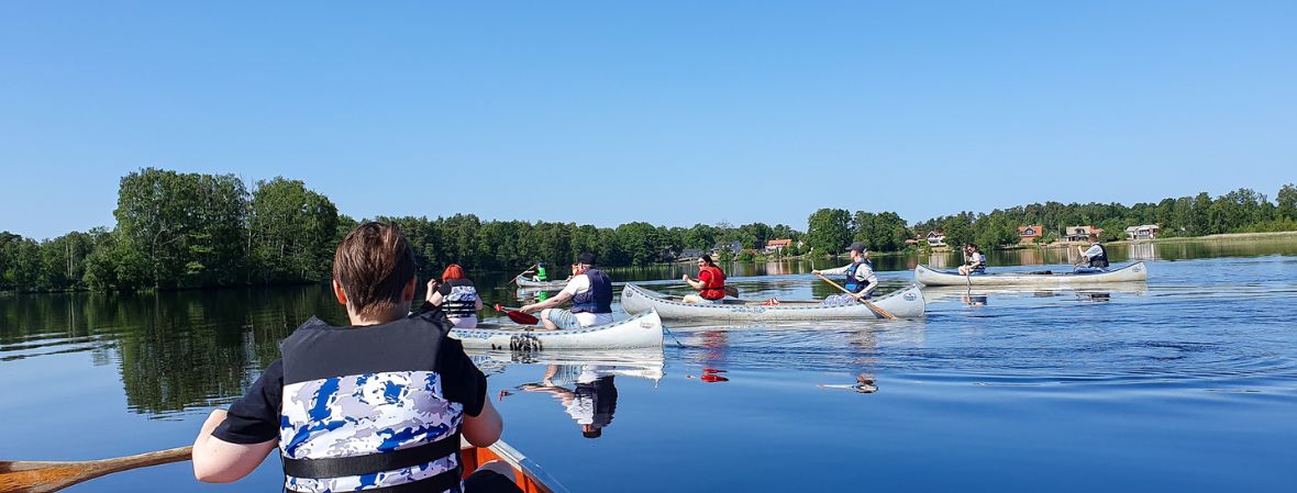 Elever paddlar kanot på sjön